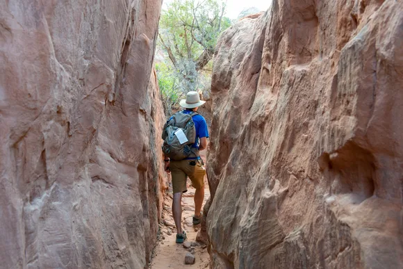 hiker with permit in narrow path between tall rock walls