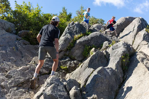 Hikers traverse large boulders at the summit of Marys Rock