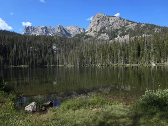 tree lined lake with a mountain backdrop